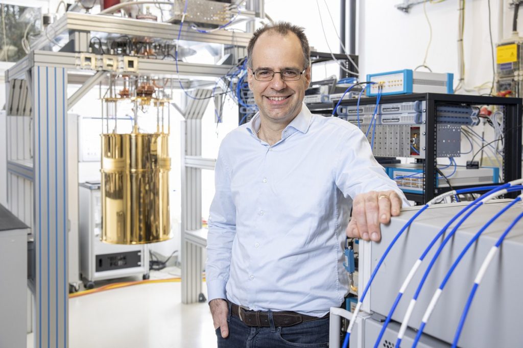 Das Foto zeigt Frank Wilhelm-Mauch lachend vor wissenschaftlichen Apparaturen in einem Labor des Forschungszentrums Jülich.